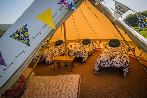 Interior shot of bell tent with cam beds, duvets and bunting