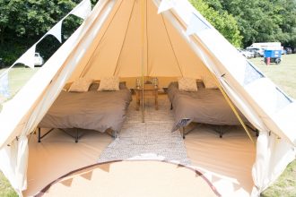 Wedding guest accommodation bell tent with double camp beds and bunting