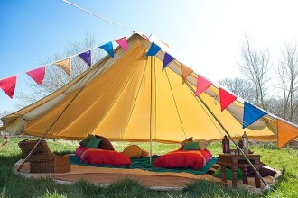 5m bell tent with the sides rolled up and dressed in Moroccan colourful style