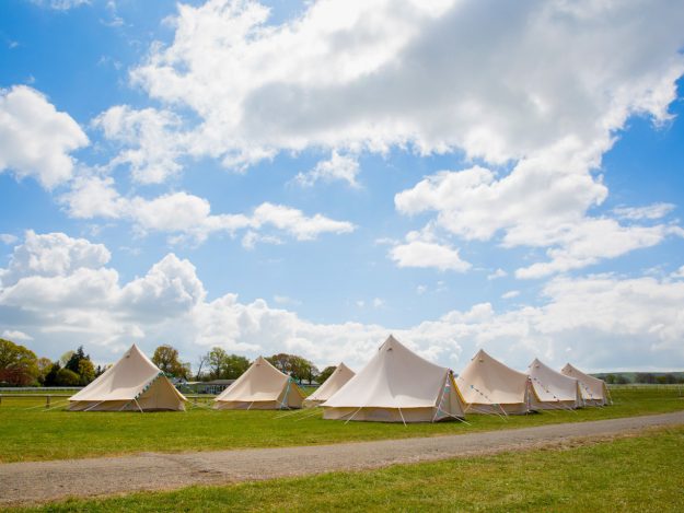 Bell tent village on the racecourse with blue skies at Plumpton Racecourse