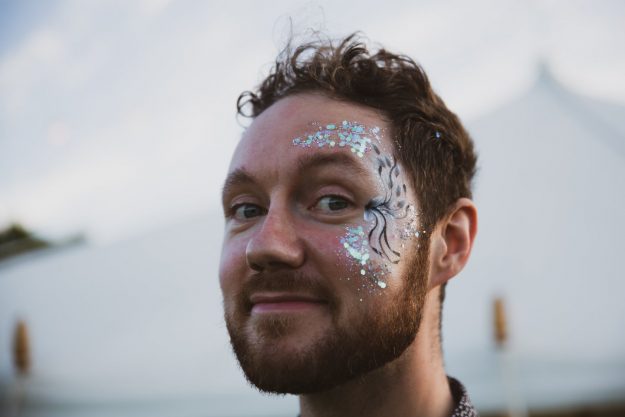 Wedding Glamping in Hampshire. Man with festival face paint. 