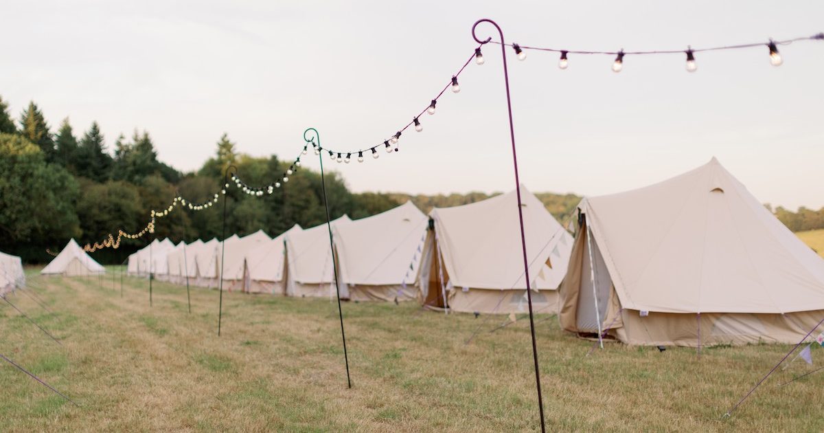 Bell Tent Hire For Weddings Imogen Xiana Photography Row of bell tent with festoon lights running through the middle. Bell tent hire for weddings in Surrey.