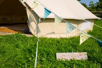 Bell tent village, 4m bell tent with bright bunting and wooden signage